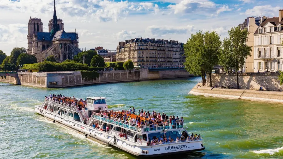 Sightseeing boat cruising the Seine under a Paris bridge